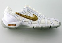 a white and gold nike tennis shoe on a white surface